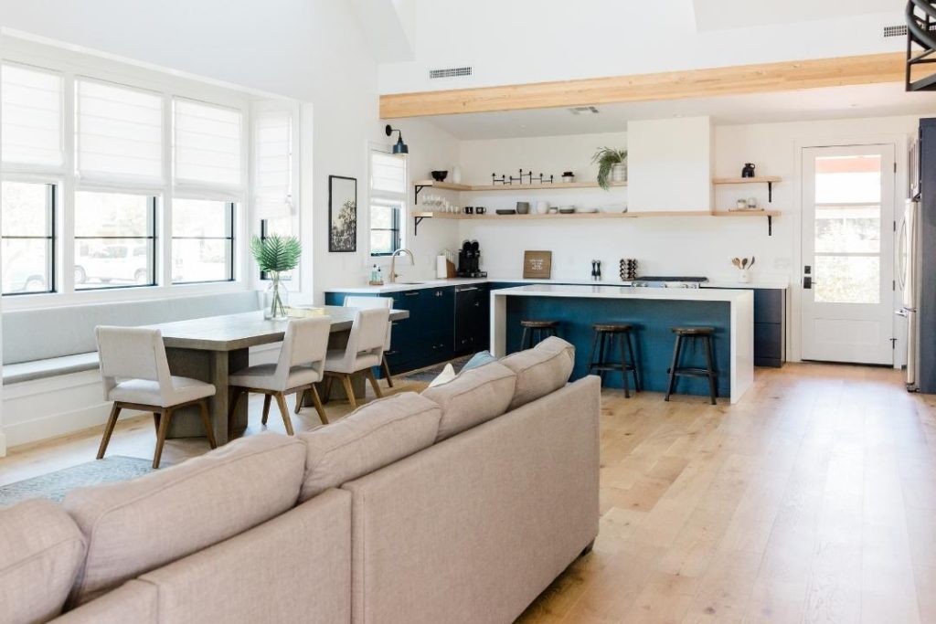 Ambiente de sala e cozinha integradas, com um espaço para sofá, mesa de jantar e um balcão que divide a cozinha.