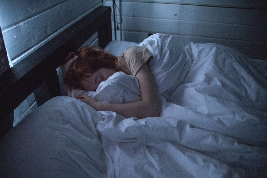 Mulher dormindo no seu quarto aproveitando suas persianas para melhorar o sono no inverno
